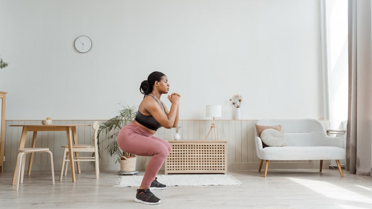 Woman in activewear doing squats at home, promoting a healthy lifestyle and fitness routine.